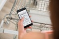 Woman Checking Shopping List On Smartphone In Supermarket Royalty Free Stock Photo