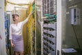 Woman checks the connection of the Internet optical wires in the server room of the data center. Girl is next to the powerful