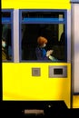 Woman checks phone while sitting in bright yellow Setagaya Tram in Tokyo