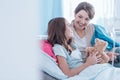 cheering up sick younger sister lying in hospital bed with teddy bear