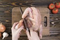 Woman chef cuts a chicken carcass on a cutting board. Domestic bird