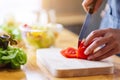 A woman chef cutting and chopping tomato by knife on wooden board Royalty Free Stock Photo