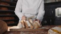 Woman chef cutting healthy bread on wooden board at bakehouse kitchen