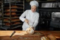 Woman chef cutting healthy bread on wooden board at bakehouse kitchen