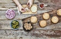 The woman-chef prepares burgers. Burger burgers and burger ingredients on a wooden kitchen table Royalty Free Stock Photo