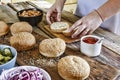 The woman-chef prepares burgers. Burger burgers and burger ingredients on a wooden kitchen table Royalty Free Stock Photo