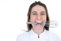 Woman chef restaurant showing whisk pastry whip in the mouth between female teeth on white background