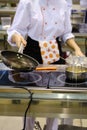 Woman chef roasts in a frying pan in the hotel`s public kitchen