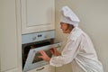 A woman in chef`s clothes turns on the oven while cooking an apple pie in the kitchen Royalty Free Stock Photo