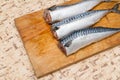 A woman chef slices a fish mackrel on a wooden Board