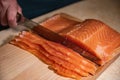 The woman chef slices or prepares fresh salmon fish fillets on the kitchen table