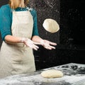 woman chef tossing pizza dough and another roll dough on a wooden board. Process of preparing pizza. Cooking time, cooking Royalty Free Stock Photo