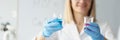 Woman chemist holding glass beakers with pink and blue liquid in front of assistant closeup Royalty Free Stock Photo