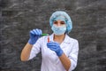 Woman chemist making experiment with test tube and flask wearing medical coat and mask