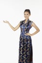Woman in cheongsam smiling with welcoming hand gesture. Conceptual image