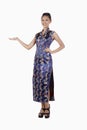 Woman in cheongsam smiling with welcoming hand gesture. Conceptual image