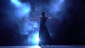 Flamenco. Woman in a chic dress turns in an incendiary dance . Llight from behind. Smoke background. Silhouette. Slow