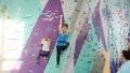 Woman with child enjoying climbing in gym while people belaying holding ropes