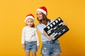 Woman child girl in Christmas Santa hat hold clapperboard. Mommy little kid daughter isolated on yellow background Royalty Free Stock Photo
