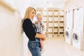 woman with a child on her hands in the laundry is waiting for cl Royalty Free Stock Photo