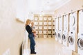 woman with a child on her hands in the laundry is waiting for cl Royalty Free Stock Photo