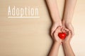 Woman and child holding heart on beige background, top view. Adoption concept