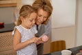 Woman, child and icing cupcake in kitchen for baking decoration with grandmother, bonding or ingredients. Female person Royalty Free Stock Photo