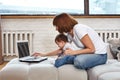 A woman with a child at a laptop sitting on a sofa. Work at home, freelancer, work during maternity leave for remote Royalty Free Stock Photo