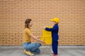 Woman and child, mother and son, pass yellow cardboard boxes from hand to hand