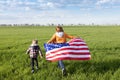 woman and a child run merrily across a green meadow,American flag fluttering behind them Royalty Free Stock Photo