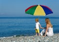 Woman and child sit under an umbrella Royalty Free Stock Photo