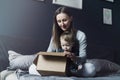 Woman and child sitting on home bed and unwrapping delivered package. Online order of high quality goods at affordable prices