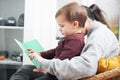 A woman and a child are sitting together and reading a book