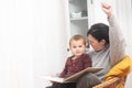 A woman and a child are sitting together and reading a book