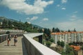 Woman and child walking on footbridge over valley with building