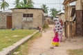 Woman with Children on the Arm at the Street of Nungwi, Zanzibar Island. Tanzania. In the Background playing small Children