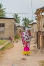 Woman with Children on the Arm at the Street of Nungwi, Zanzibar Island. Tanzania. In the Background playing small Children