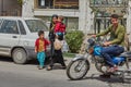 Woman with children crossing road in front of motorbike, Iran.