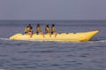 A woman with children rides on a yellow banana boat