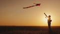 Woman With a children`s backpack behind her back runs a kite at sunset. Dream and return to childhood concept