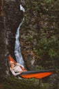 Woman chilling in hammock in forest outdoor camping gear summer vacations girl enjoying waterfall view in Norway Royalty Free Stock Photo