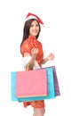 Woman in Chinese dress holding colorful shopping bag.