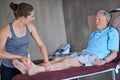 Woman, chiropractor and senior patient with joint pain in elderly care for muscle or leg injury at clinic. Female person Royalty Free Stock Photo