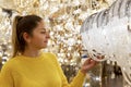 A woman chooses a beautiful expensive chandelier in the salon. Young blonde in a yellow sweater