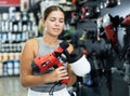 Woman chooses and buys paint spray gun in hardware store Royalty Free Stock Photo