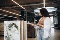 A woman chooses ceramic tiles in a hardware store. A beautiful blonde in a black jacket touches samples in a showcase Royalty Free Stock Photo