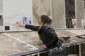 A woman chooses ceramic tiles in a hardware store. A beautiful blonde woman in a black jacket touches samples in a showcase. Royalty Free Stock Photo