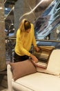 A woman chooses fabric for upholstery of a sofa in a furniture showroom. Young blonde in a yellow sweater. Interior design and