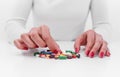 Woman chooses medicine from a handful of different color tablets. Royalty Free Stock Photo