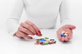 Woman chooses medicine from a handful of different color tablets. Royalty Free Stock Photo